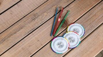 Set of colorful crochet hooks and several wheels of sewing pins arranged neatly on a wooden surface. photo