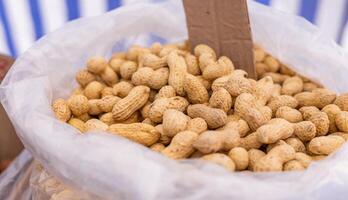 Peanuts in a bag at the market. Unpeeled peanuts texture. Top view, flat lay, copy space. photo