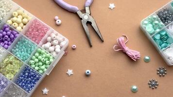 Crafting with colorful beads on a flat workspace with tools and containers in bright daylight video