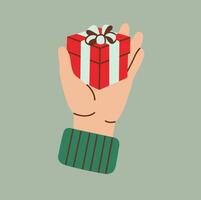 Flat style illustration of a hand holding a small red gift box with a ribbon and bow on a pastel green background. Perfect for holiday-themed projects, greetings, and festive designs. vector