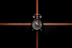 The alarm clock puts in the middle of green and red color ribbon on black background for Black Friday shopping day concept. photo