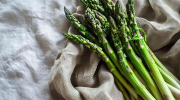 bunch of green asparagus, lay in the right corner, isolated on light tablecloth photo