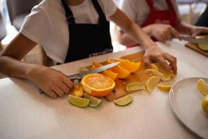 close-up shot. children's hands cut citrus fruits for making lemonade at a culinary master class photo