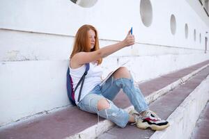 teenage girl draws in the sketchbook while sitting on the steps photo