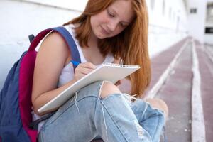 teenage girl draws in the sketchbook while sitting on the steps photo