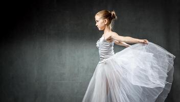 Ballerina. Cute little girl posing and dancing in studio. The girl is studying ballet. Dark background. photo