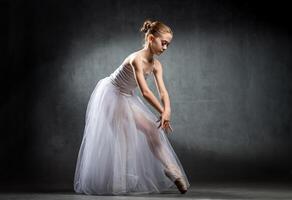 Ballet. Image of a flexible cute ballerina dancing in the studio. Beautiful young dancer. A ballerina is posing. photo