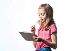 Little girl with a tablet computer and candy on a white background. Emotions of the child. photo