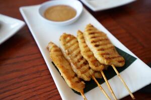Close up Pork Satay skewers served with thick peanut dipping sauce photo