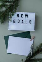Lightbox with inspirational message NEW GOALS with fir branches on pastel background. Happy new year promises resolutions concept. Copy space envelope mock up sample Self growth and personal development photo