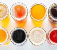 A colorful assortment of beer glasses showcasing different types and colors on a white background, top view photo