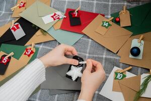 Number on craft envelopes notes with tasks before Christmas holidays. Female making kraft paper for handmade advent calendar Made with your own hands step by step DIY crafts do it yourself photo
