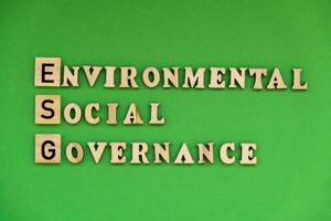 ESG inscription ENVIRONMENTAL SOCIAL GOVERNANCE investment business concept. Text on wooden block on green background. Society and corporate governance photo