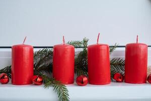 New year and Christmas preparation. Four red advent candles in white windowsill. Handmade eco-friendly decor. Sustainable Christmas decoration. Copy space photo