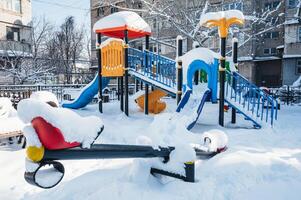 Snowcovered playground with slide and swings in winter wonderland city photo