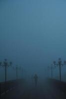 mystical silhouettes of people on a foggy bridge in the evening in autumn in fog mist photo