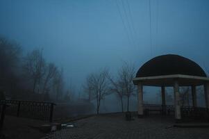 misty landscape with a gazebo by river on an autumn morning in the fog mist photo