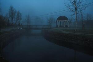 misty landscape with a gazebo by river on an autumn morning in the fog mist photo