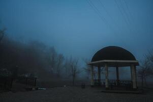 misty landscape with a gazebo by river on an autumn morning in the fog mist photo