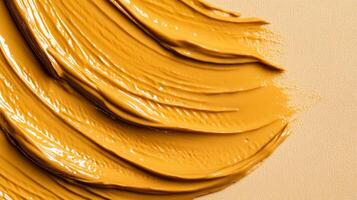 Closeup of golden brown eyebrow gel with tiny microfibers creating a textured pattern against a light tan background photo