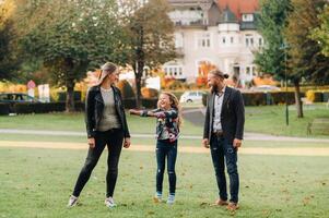 A happy family of three runs through the grass in Austria's old town.A family walks through a small town in Austria.Europe.Velden am werten Zee photo