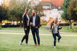 A happy family of three runs through the grass in Austria's old town.A family walks through a small town in Austria.Europe.Velden am werten Zee photo