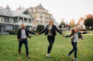 A happy family of three runs through the grass in Austria's old town.A family walks through a small town in Austria.Europe.Velden am werten Zee photo