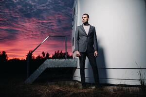 A man in a grey business suit stands next to a windmill after sunset .Businessman near windmills at night.Modern concept of the future. photo