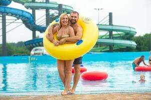 a man and a woman in a rubber inflatable circle stand against the background of a summer water park pool photo