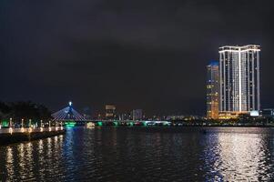 Night panorama of Da Nang city with a Han River Bridge over Han river and skyscrapers hotels in Vietnam photo