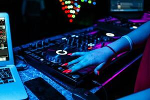 girl DJ mixes music with her hands on a music mixer in a night club at a party photo