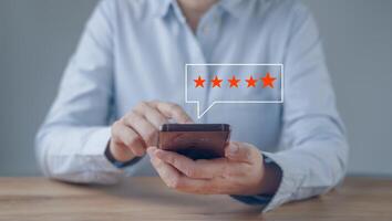 Close up woman hand using smartphone with popup five star rate icon for positive feedback review ,opinion service, questionnaire report. Customer service experience and business satisfaction survey. photo