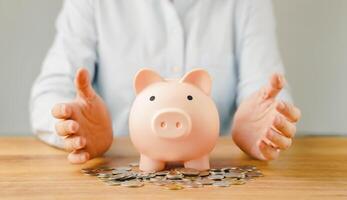 Hand holding piggy bank on wood table. Save money for wealth, financial investment business, future education concept with copy space for input text. photo