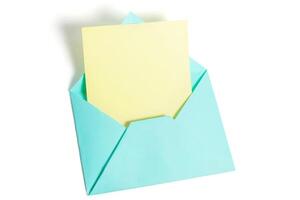 Top view of open blue envelope with yellow paper sheet isolated on white background. photo