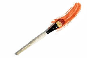 Vibrant red paint stroke on a white background with a brush to paint over it, top view photo