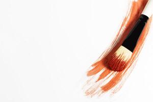 Red paint stroke on a white background with a brush to paint over it photo