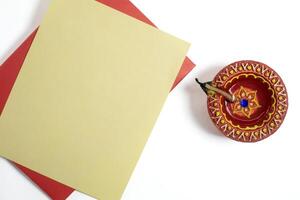 Handmade clay diya lamp with blank greeting card for Diwali festival greetings on white background photo