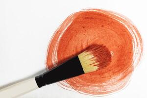 Vibrant red paint stroke on a white background with a brush to paint over it photo