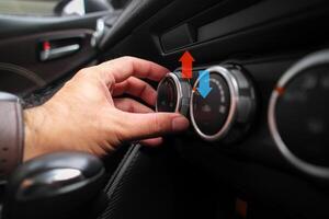 Adjusting the temperature of air conditioning inside a car , The driver uses his hands to turn the knob to adjust the air conditioning temperature while driving photo