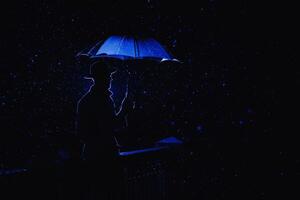silhouette in the noir style of a male mafia detective in a raincoat and hat under an umbrella photo