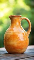 A rustic brown clay pitcher on a wooden surface with a blurred green background. photo