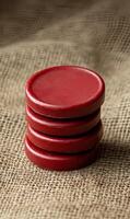 Four red game pieces stacked on burlap fabric. photo