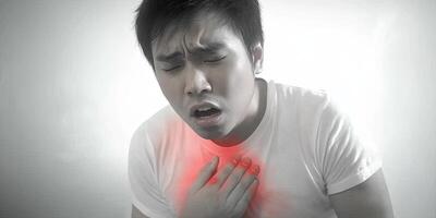 A man with a pained expression, clutching his chest, is experiencing chest pain, possibly a heart attack. photo