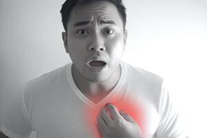 A young man experiencing chest pain, clutching his chest with a pained expression. photo