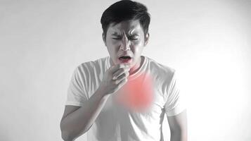 A man coughs, covering his mouth with his hand. He has a red area on his chest, suggesting he is sick. photo