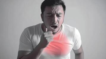 A man with a cough and a red spot on his chest, holding his chest, looking uncomfortable. photo