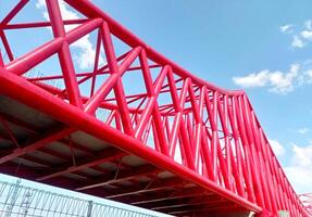 construction of the Indonesian railway bridge. a red structure with a blue sky and clouds photo