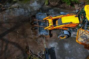 A bulldozer collects branches after pruning trees. View from above photo