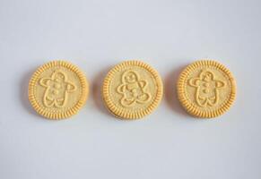 Round cookies with including Christmas symbols such as trees, snowmen and other holiday characters. Vanilla or butter sandwich cookies. photo
