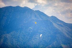 People paragliding over the beautiful mountains of the Antioquia department in Colombia. Tandem Paragliding. Extreme sport concept. photo